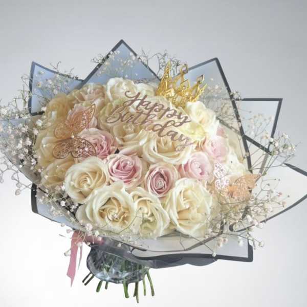 Bouquet of cream and pink roses with a "Happy Birthday" topper