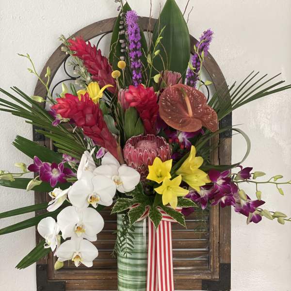 Tropical flower arrangement in a glass vase with orchids and red blooms