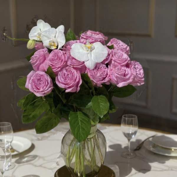 Pink roses and white orchids in a glass vase on a table