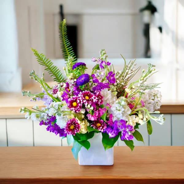 Mixed purple and white flowers in a white square vase