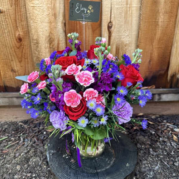 Mixed bouquet of red, pink, and purple flowers in a glass vase