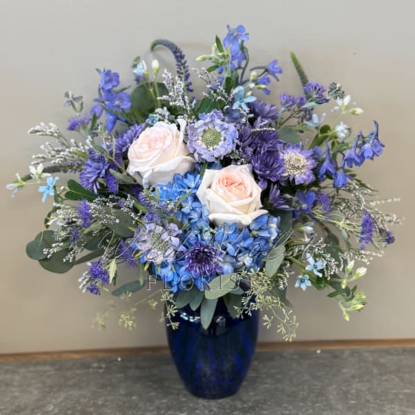 Blue and lavender floral arrangement in a dark blue vase