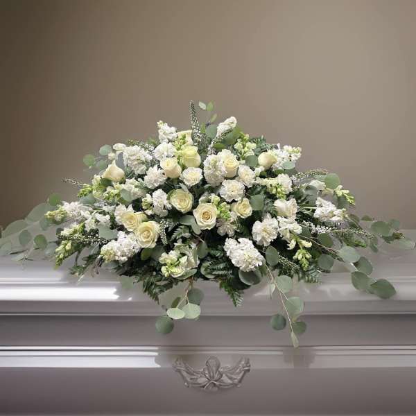 White floral casket spray with roses and greenery