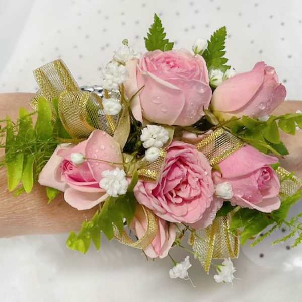 Pink rose wrist corsage with gold ribbon and white filler flowers