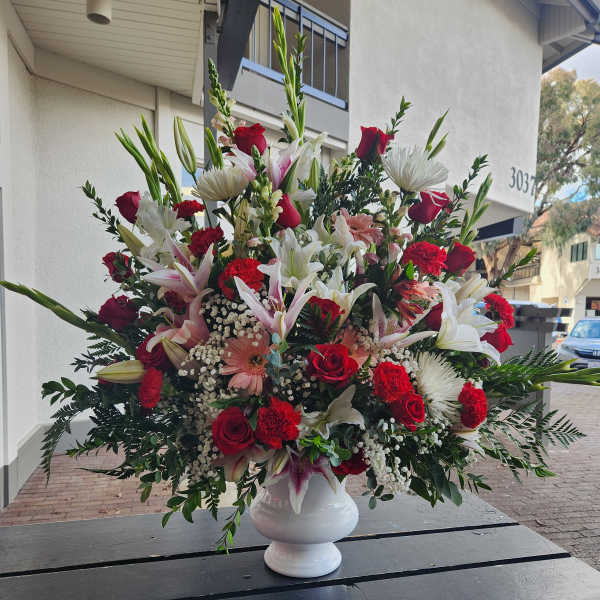 Large mixed bouquet in a white urn vase with red, white, and pink flowers