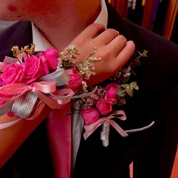 Pink rose corsage on a suit wrist with ribbon accents