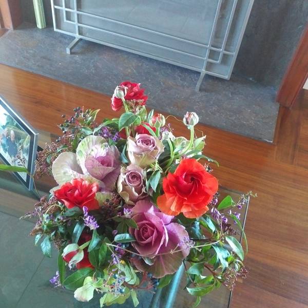 Mixed bouquet with red, pink, and purple flowers in a glass vase