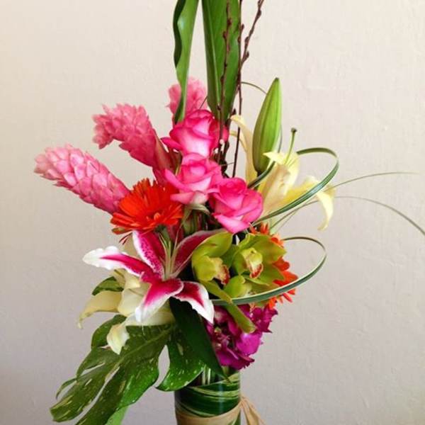Tall tropical bouquet with pink and white flowers in a wrapped vase