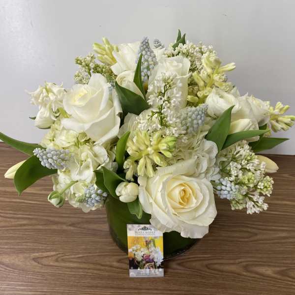 White rose and mixed white flower arrangement in a green vase
