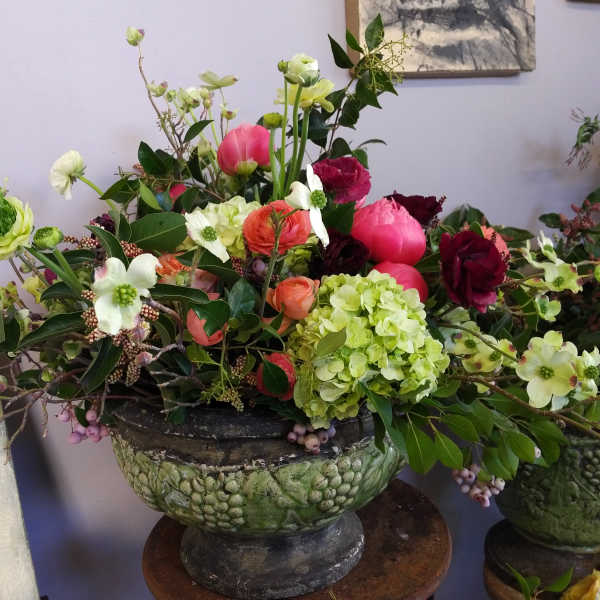 Large mixed floral arrangement in a green pedestal bowl