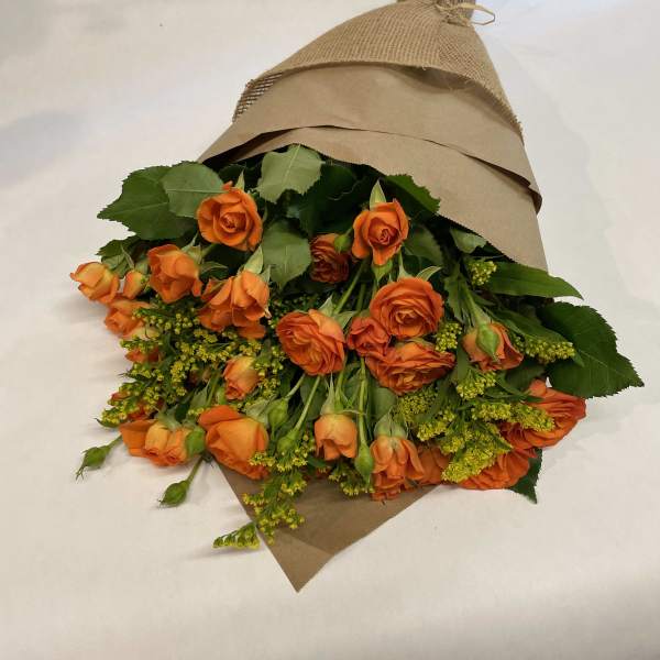 Bouquet of orange roses wrapped in brown paper