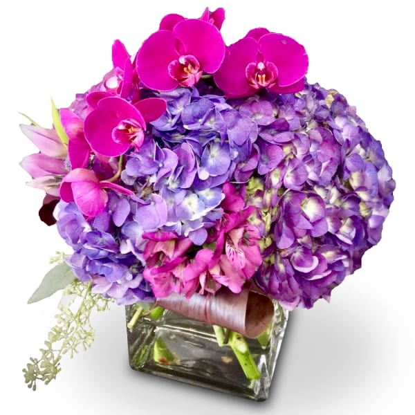 Purple hydrangea bouquet with pink orchids in a glass vase