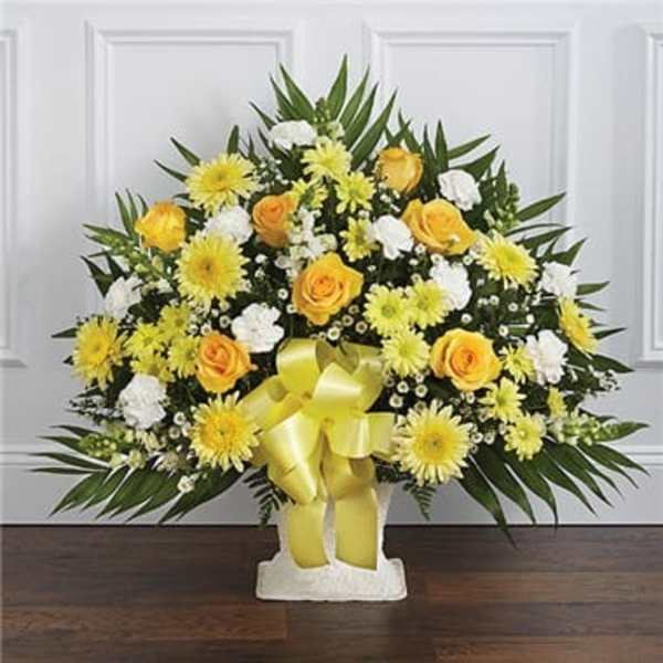 Yellow and white floral arrangement with a ribbon on a pedestal base