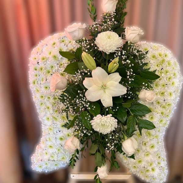 Standing white floral arrangement with chrysanthemum wings and central roses and lilies