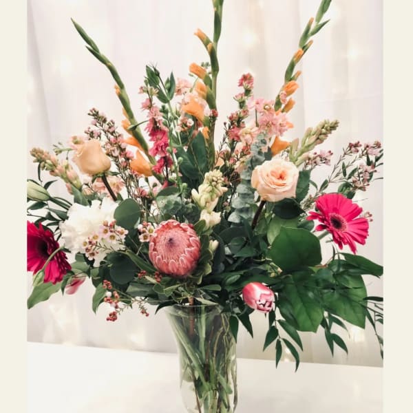 Tall mixed bouquet in a clear glass vase with pink and peach blooms