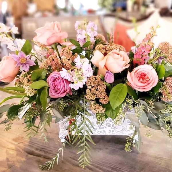 Pink and lavender roses arranged in a white decorative container
