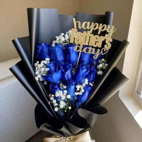 Blue roses with baby's breath in black wrap and a gold Father's Day topper