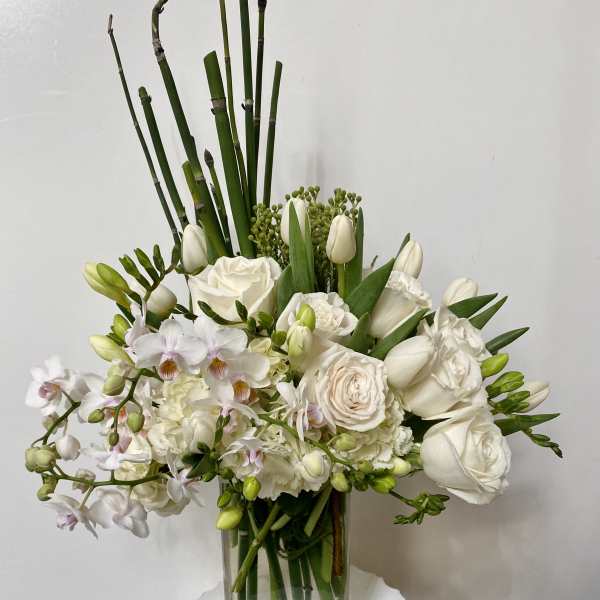 White floral arrangement in a clear glass vase with tall green stems