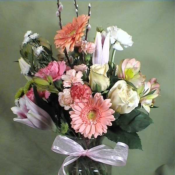 Mixed pink and white flowers in a glass vase with a ribbon