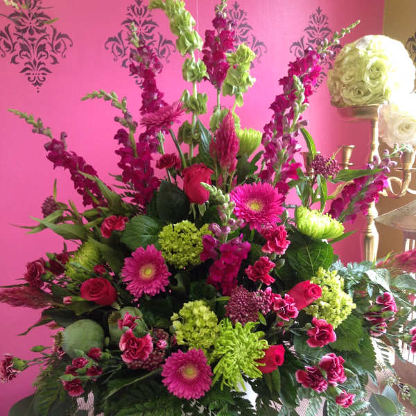 Large pink and green floral arrangement in a white vase