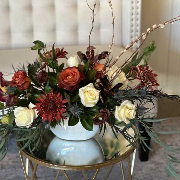 Mixed roses and burgundy flowers arranged in a white vase
