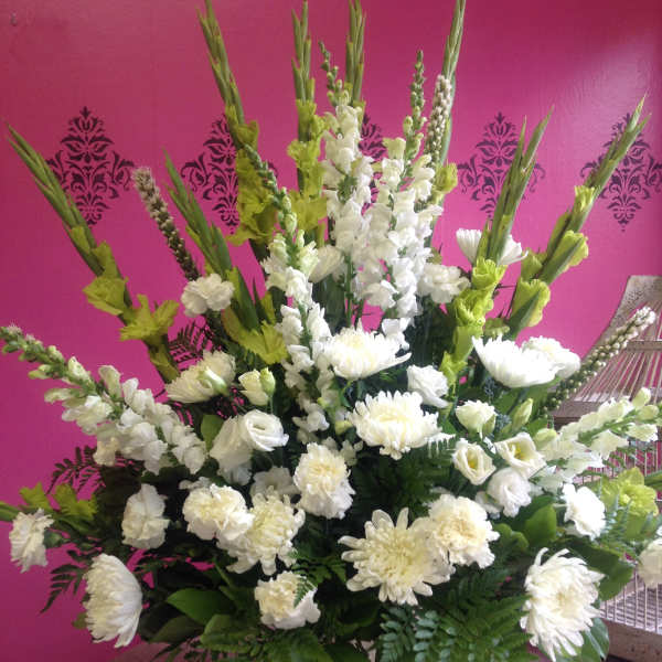 Tall white floral arrangement in a white vase with green accents