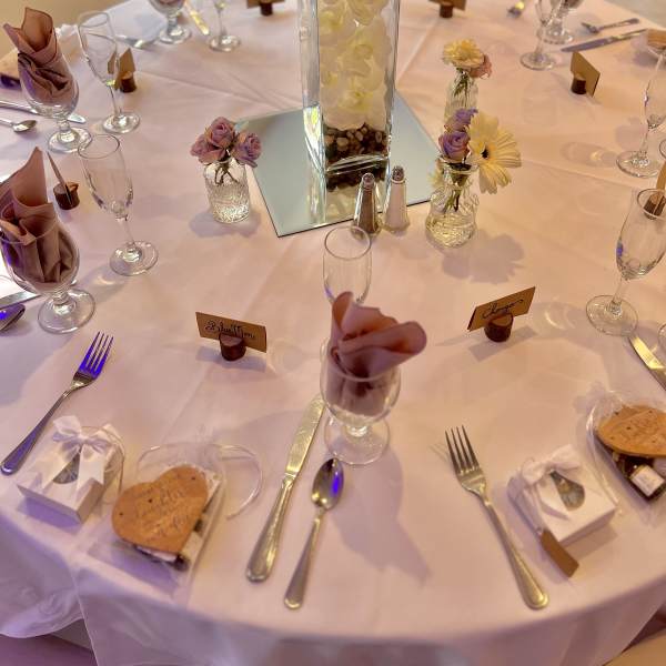 Round table with small floral vases and a tall white centerpiece