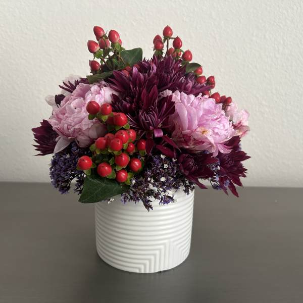 Pink and purple floral arrangement in a white ribbed vase