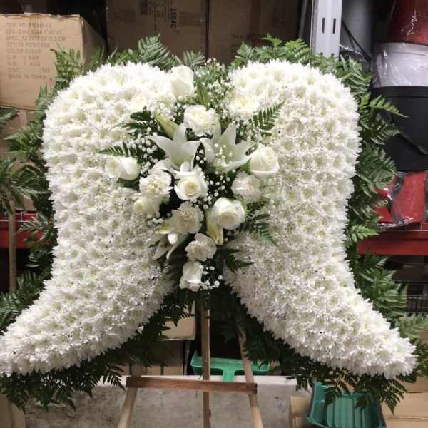 White funeral spray on an easel with roses and lilies