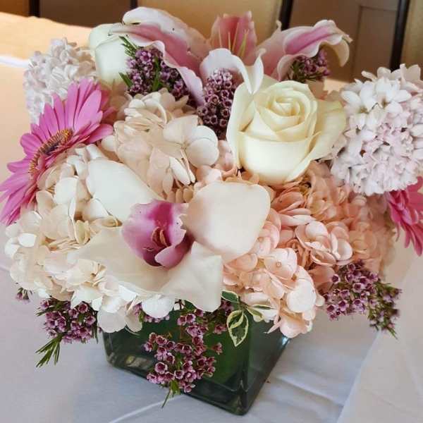 Pink and white floral arrangement in a square glass vase