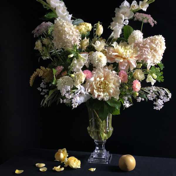 Tall pastel floral arrangement in a clear glass vase with white and blush blooms