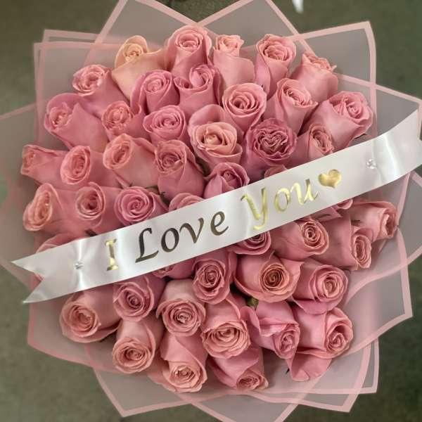 Bouquet of pink roses wrapped with a ribbon that says "I Love You"
