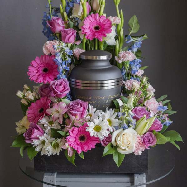 Funeral urn surrounded by pink, white, and blue flowers