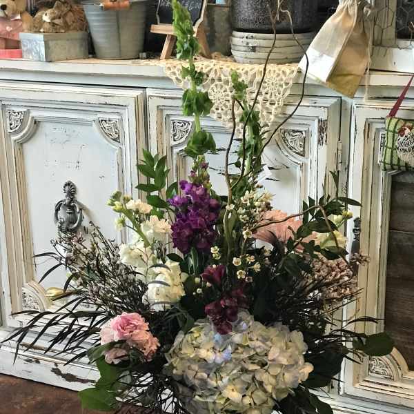 Tall mixed flower arrangement in a glass vase with purple, white, and pink blooms