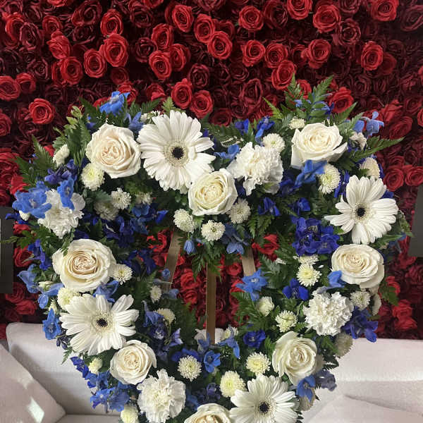 Heart-shaped floral wreath with white roses, daisies, and blue flowers