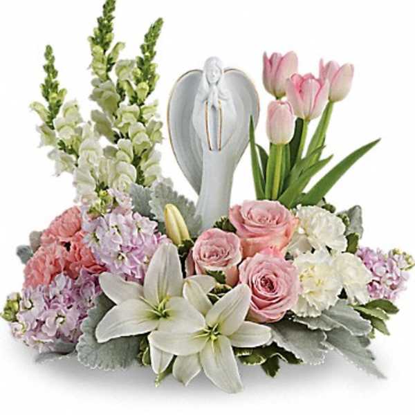 Pink and white floral arrangement with lilies, roses, tulips, and an angel figurine