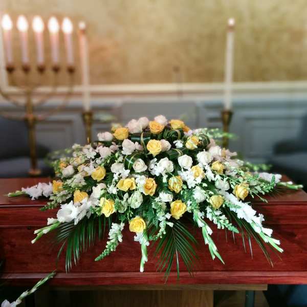 White and yellow rose arrangement on a wooden casket