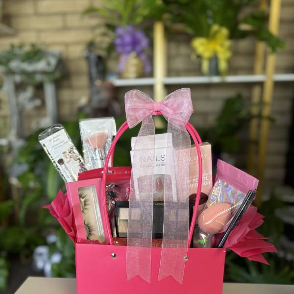 Pink gift basket with makeup items and a sheer bow
