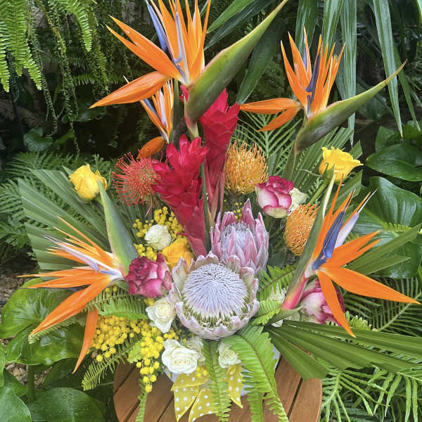 Tropical bouquet with orange bird-of-paradise and pink protea in a vase