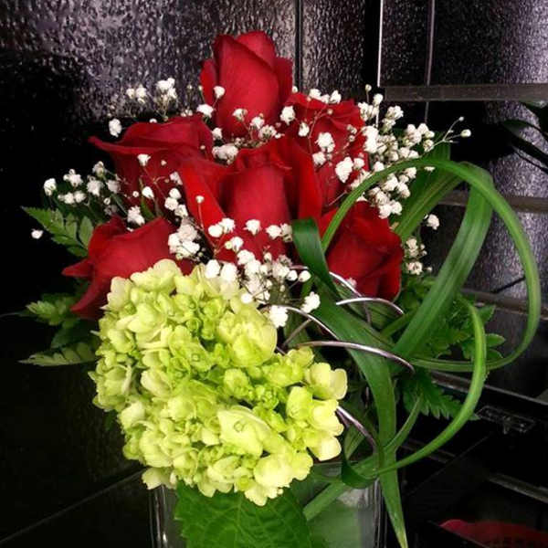 Red roses and green hydrangea in a clear glass vase