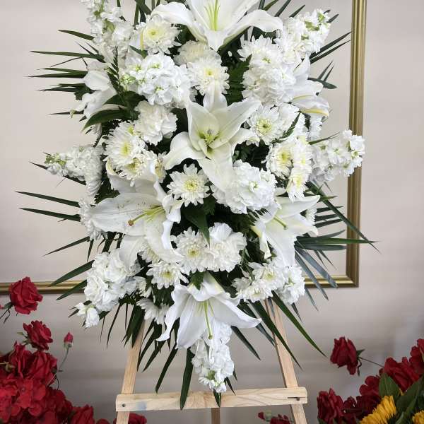 Tall white floral standing spray with lilies and chrysanthemums on an easel