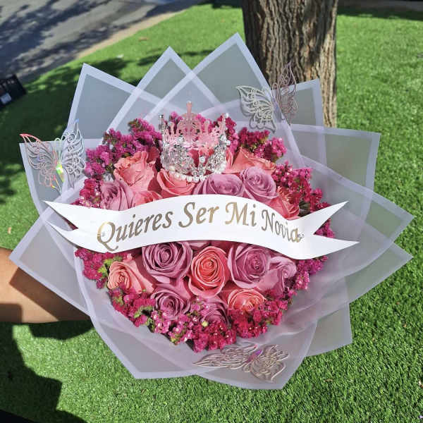 Pink rose bouquet with a crown topper and a "Quieres Ser Mi Novia" banner