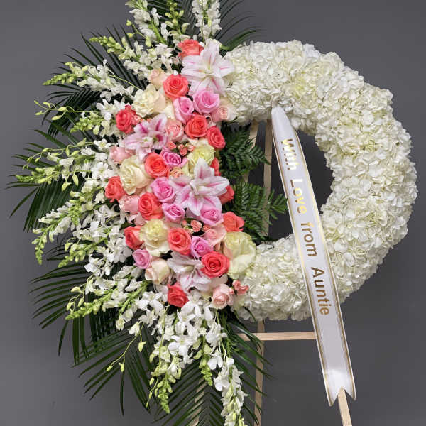 Heart-shaped floral wreath with pink and white flowers and a ribbon