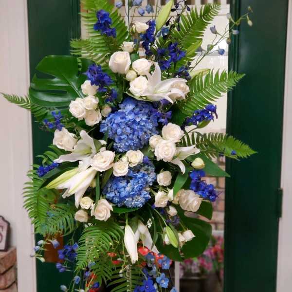Tall blue and white floral arrangement with lilies, roses, and hydrangeas