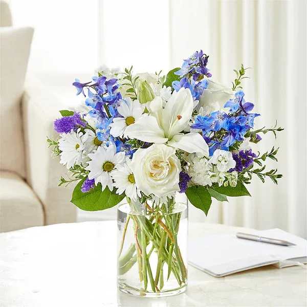White and blue mixed bouquet in a clear glass vase