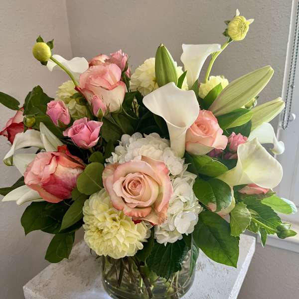 Pink roses and white calla lilies in a clear glass vase