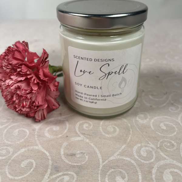 Soy candle in a glass jar beside a pink carnation