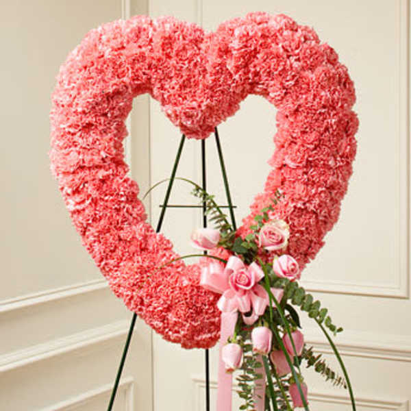 Pink heart-shaped floral wreath on an easel with a small pink rose bouquet