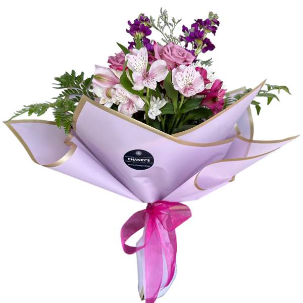 Bouquet of pink and purple flowers wrapped in lavender paper with a ribbon