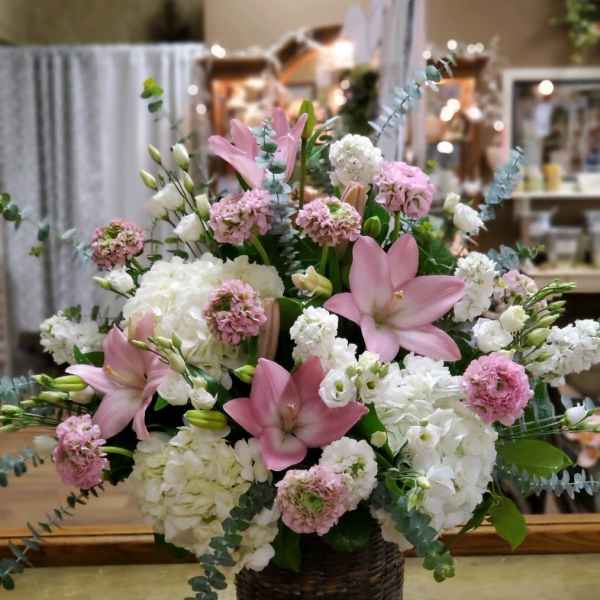 Pink lilies and white hydrangeas in a dark woven basket
